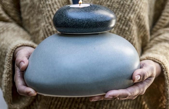 Eternity Pebble Child/Infant Memorial Urn close up with memorial candle held by grieving woman